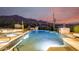 Stunning pool with integrated spa, waterfall features, and desert landscaping against a backdrop of mountains at dusk at 36075 N Summit Dr, Cave Creek, AZ 85331