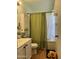 Bright bathroom with traditional cabinets, white shower curtain and a green accent wall at 12512 N 85Th Ave, Peoria, AZ 85381