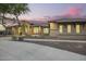 Well-maintained single-story home with desert landscaping and warm exterior lighting at twilight at 14188 W Hope Dr, Surprise, AZ 85379