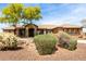 Charming desert home with mature landscaping, including trees, bushes, and rock accents at 14188 W Hope Dr, Surprise, AZ 85379