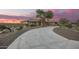 Beautiful desert home at sunset with an expansive driveway, mature trees, and xeriscaping at 14188 W Hope Dr, Surprise, AZ 85379