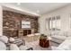 Stylish living room featuring a brick accent wall, comfortable seating, and natural light from the windows at 14188 W Hope Dr, Surprise, AZ 85379
