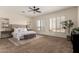 Bright main bedroom featuring a tufted headboard, ceiling fan, large windows and a serene outdoor view at 14188 W Hope Dr, Surprise, AZ 85379