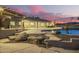 Outdoor living space with a pool, built-in grill, stone patio, and lush landscaping at 14188 W Hope Dr, Surprise, AZ 85379