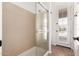 Tiled walk-in shower with glass doors, modern fixtures and an adjacent door to the exterior at 14188 W Hope Dr, Surprise, AZ 85379
