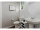 Small bathroom with toilet, sink, small cabinet, mirror, and unique wall decor at 16022 W Desert Mirage Dr, Surprise, AZ 85379