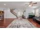 Bright living room with hardwood floors, a ceiling fan, and a decorative rug leading to the front door at 16022 W Desert Mirage Dr, Surprise, AZ 85379
