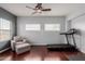 Bright sitting room features a cozy armchair, a treadmill and two large windows at 16022 W Desert Mirage Dr, Surprise, AZ 85379