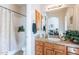 A well-lit bathroom with a vanity, mirror, and shower with a patterned shower curtain at 16441 S Mountain Stone Trl, Phoenix, AZ 85048