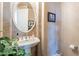 Stylish half bath features a decorative mirror, pedestal sink, and tile accents at 16441 S Mountain Stone Trl, Phoenix, AZ 85048