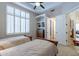 Comfortable bedroom featuring two beds, plantation shutters, ceiling fan, and built-in shelving at 16441 S Mountain Stone Trl, Phoenix, AZ 85048