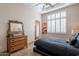 A well-lit bedroom with a window, ceiling fan, and wooden furniture at 16441 S Mountain Stone Trl, Phoenix, AZ 85048