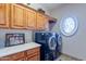 Well-organized laundry room featuring ample cabinetry, a decorative window, countertop space and modern washer and dryer at 16441 S Mountain Stone Trl, Phoenix, AZ 85048