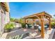 Relaxing backyard with a charming pergola-covered patio seating area, set against a backdrop of lush greenery and blue skies at 17054 W Saguaro Park Ln, Surprise, AZ 85387