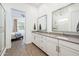 Bathroom with dual sinks, white cabinets, and a glass-enclosed shower at 17054 W Saguaro Park Ln, Surprise, AZ 85387