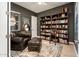 Cozy library bedroom with a leather chair, ottoman, and floor-to-ceiling bookshelves creating a study room at 17054 W Saguaro Park Ln, Surprise, AZ 85387