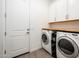 Well-lit laundry room includes a side-by-side washer and dryer with storage and white cabinets above at 17054 W Saguaro Park Ln, Surprise, AZ 85387