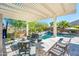Outdoor living space with a large pool, outdoor seating area, a bar, and a covered patio with a TV at 17054 W Saguaro Park Ln, Surprise, AZ 85387