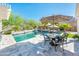 Inviting pool area featuring a patio table with umbrella, lush landscaping, and a serene water feature at 17054 W Saguaro Park Ln, Surprise, AZ 85387