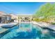 Swimming pool with outdoor kitchen and seating under a bright blue sky at 17054 W Saguaro Park Ln, Surprise, AZ 85387