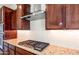 Close up of cooktop with stainless steel vent hood, granite countertop and tile backsplash at 18840 N 269Th Ave, Buckeye, AZ 85396