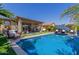 Inviting pool with comfortable patio seating, lush plantings, turf accent and blue umbrella at 20839 E Kingbird Dr, Queen Creek, AZ 85142