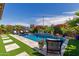 Lush pool with manicured artificial turf, tiled accents, patio set and flowering shrubbery at 20839 E Kingbird Dr, Queen Creek, AZ 85142