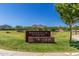 Welcome to Siennahills Compass Park sign with beautiful green landscaping and scenic mountain views at 21412 W Hubbell St, Buckeye, AZ 85396