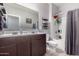 Bathroom with double vanity, tiled floors, shelves, toilet, and shower over tub with curtain at 2458 N Abbey Rd, Casa Grande, AZ 85122