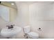 Powder room with pedestal sink, round mirror, white toilet, and a window at 3530 S Bandit Rd, Gilbert, AZ 85297