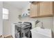 Convenient laundry room featuring a utility sink, upper cabinets, and modern washer and dryer units at 3745 E Flamingo Way, Gilbert, AZ 85297