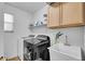 Functional laundry room with modern washer and dryer, storage cabinets, and sink at 3745 E Flamingo Way, Gilbert, AZ 85297