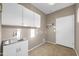 Clean laundry room features a stainless steel sink, white cabinets, and neutral tiled flooring at 42318 W Abbey Rd, Maricopa, AZ 85138
