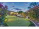 Private backyard putting green enhanced by colorful plants and landscape lighting at 42318 W Abbey Rd, Maricopa, AZ 85138