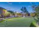 Backyard putting green surrounded by mature landscaping and an outdoor grilling area at 42318 W Abbey Rd, Maricopa, AZ 85138