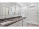 Bright bathroom with granite counters, dual sinks, and shower with built-in shelving at 5106 E Midnight Star Dr, San Tan Valley, AZ 85143