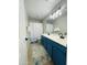 Bathroom boasts double sinks, blue cabinets, a stylish mirror, and patterned shower curtain at 7136 N 73Rd Dr, Glendale, AZ 85303