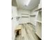 Large walk-in closet featuring wood-look flooring, multiple shelves and a centered bench at 7136 N 73Rd Dr, Glendale, AZ 85303