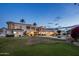 Expansive backyard featuring a large home with a pool, lush greenery, and swaying palm trees at dusk at 11809 S Montezuma Ct, Phoenix, AZ 85044