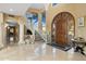 Spacious foyer featuring large windows, marble floors, a striking staircase, and a custom wooden door at 11809 S Montezuma Ct, Phoenix, AZ 85044