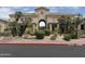 Elegant clubhouse entrance with archway, mature landscaping, and manicured flower beds at 16013 S Desert Foothills Pkwy # 2056, Phoenix, AZ 85048