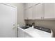 Bright laundry room equipped with a front load washer, dryer, and overhead storage cabinets for laundry supplies at 16246 W Talara Way, Surprise, AZ 85374