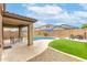 Beautiful backyard with covered patio, in-ground pool, artificial grass, and lounge area with blue umbrellas at 17424 W Willow Ave, Surprise, AZ 85388