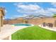Beautiful backyard with in-ground pool, artificial grass, lounge area with blue umbrellas, and privacy wall at 17424 W Willow Ave, Surprise, AZ 85388