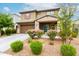 This two-story home features a stone-accented facade, a two-car garage, and vibrant flowering bushes at 17424 W Willow Ave, Surprise, AZ 85388