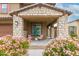 Cozy front porch with stone pillars, outdoor seating, and flowering bushes create a welcoming entrance at 17424 W Willow Ave, Surprise, AZ 85388