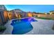 Backyard pool lit up at night with desert landscaping and lounge area seating around a modern fire pit at 17424 W Willow Ave, Surprise, AZ 85388