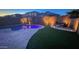 Pool area lit up at night, featuring an outdoor lounge area, and desert landscaping in the backyard at 17424 W Willow Ave, Surprise, AZ 85388