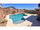 Beautiful backyard pool area with desert landscaping, a rock wall, and a patio area with an umbrella for shade at 17424 W Willow Ave, Surprise, AZ 85388