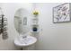 Stylish powder room with a pedestal sink, decorative mirror, and elegant wall art at 17424 W Willow Ave, Surprise, AZ 85388